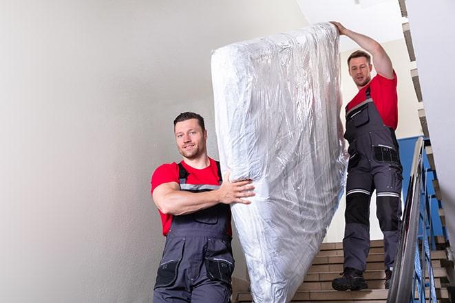 team of workers lifting a box spring out of a house in Bloomingdale